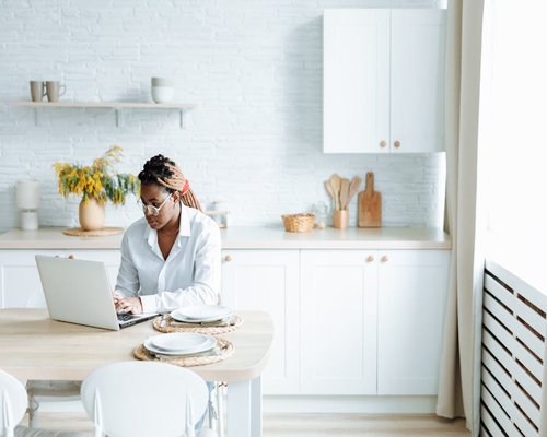 A person working on a laptop at a kitchen table