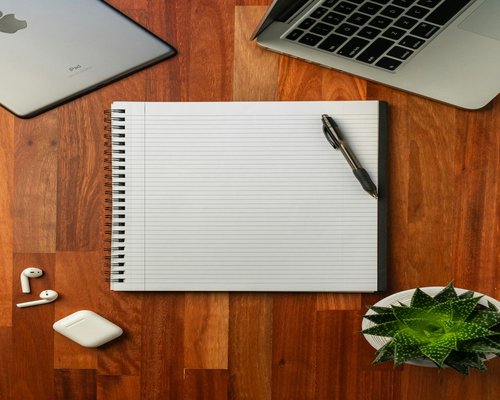 Writing notes in a notebook on a wooden desk